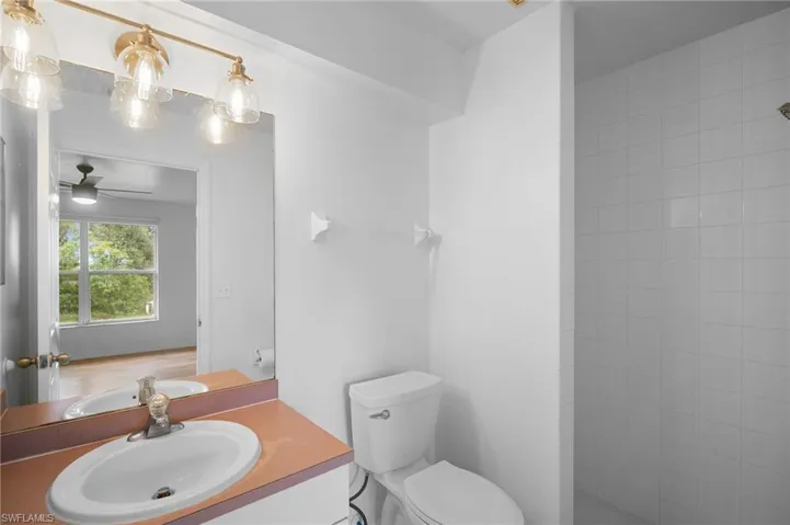 Bathroom featuring vanity, ceiling fan, and tiled shower