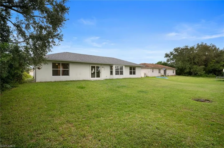 Back of house with a lawn and stucco siding