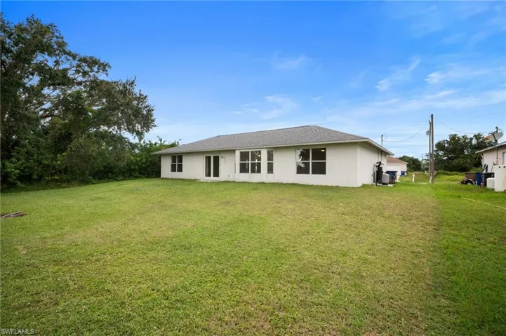 Back of property featuring a lawn and stucco siding