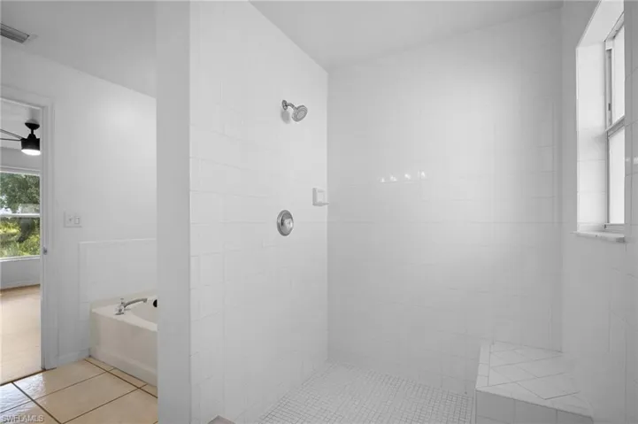 Bathroom featuring a bath, light tile patterned floors, tiled shower, and ceiling fan
