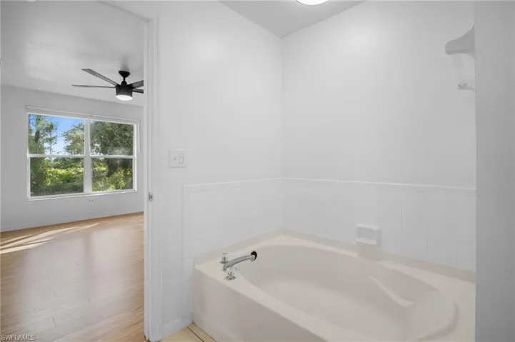 Bathroom featuring a bath, ceiling fan, and light wood-style floors