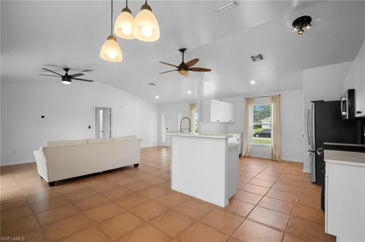Kitchen featuring white cabinets, vaulted ceiling, light countertops, pendant lighting, and open floor plan