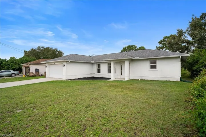 Single story home featuring concrete driveway, a front lawn, an attached garage, and stucco siding