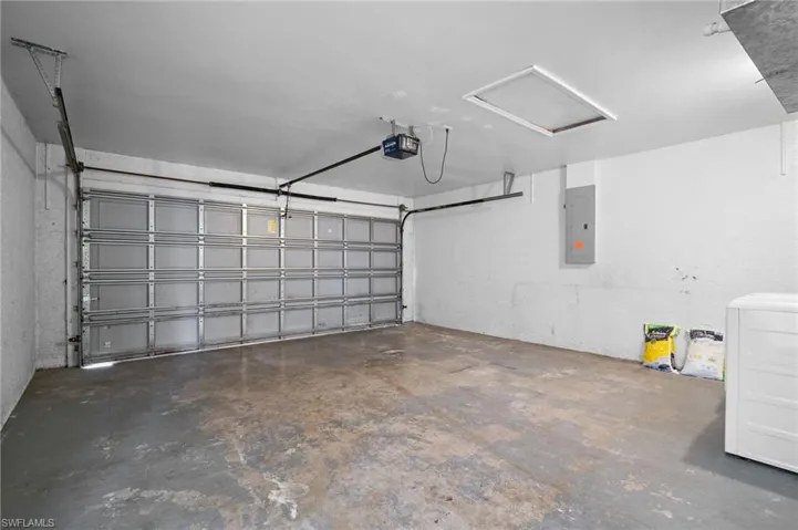 Garage with washer / clothes dryer, electric panel, and a garage door opener
