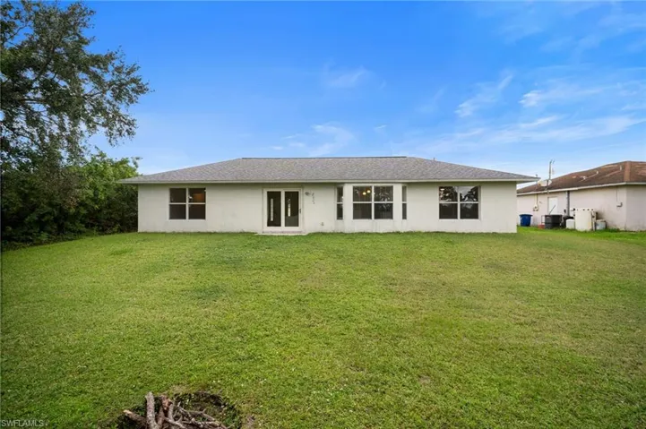 Back of house featuring a yard and stucco siding