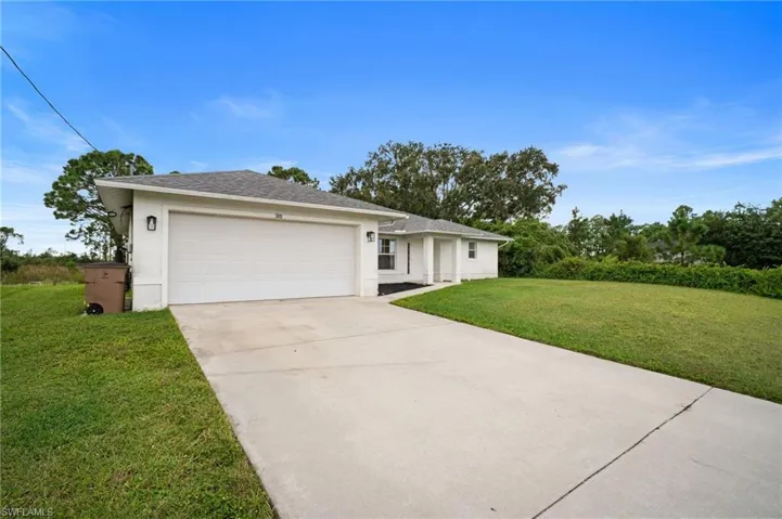 Single story home featuring stucco siding, concrete driveway, a front yard, an attached garage, and roof with shingles