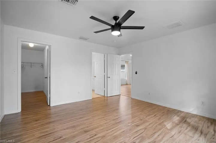 Unfurnished bedroom with light wood finished floors, a spacious closet, and ceiling fan