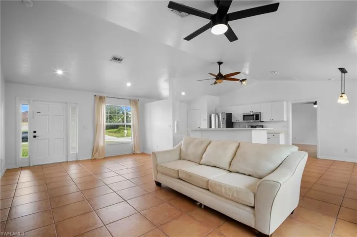 Living area with vaulted ceiling, light tile patterned floors, and recessed lighting