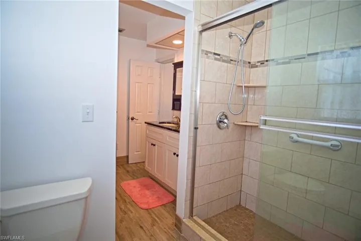 Full bath featuring a tile shower, vanity, and light wood finished floors
