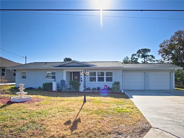 Ranch-style home with driveway, a front yard, stucco siding, and an attached garage