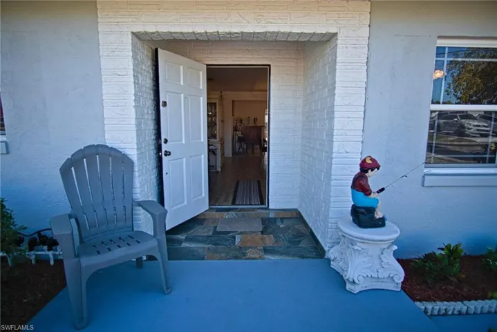 Doorway to property with covered porch and brick siding