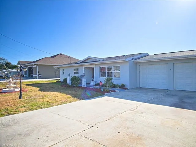 Ranch-style home with a front lawn, driveway, stucco siding, and an attached garage