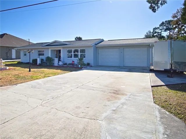 Ranch-style house with driveway, a garage, a front lawn, stucco siding, and roof with shingles