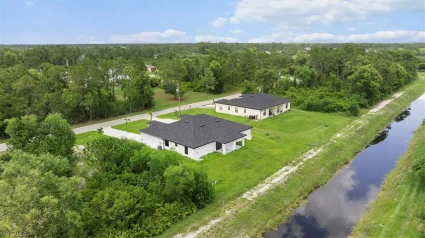 View from above of property with a nearby body of water and a forest