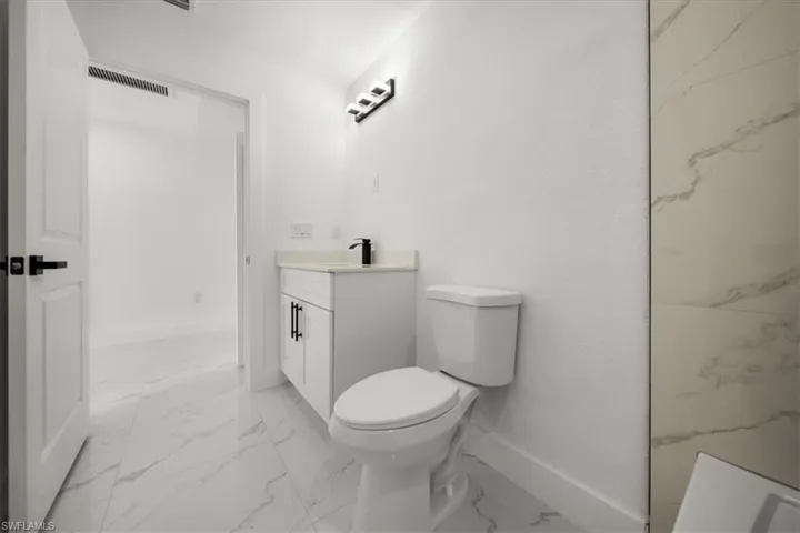 Full bath with marble look tile flooring and vanity