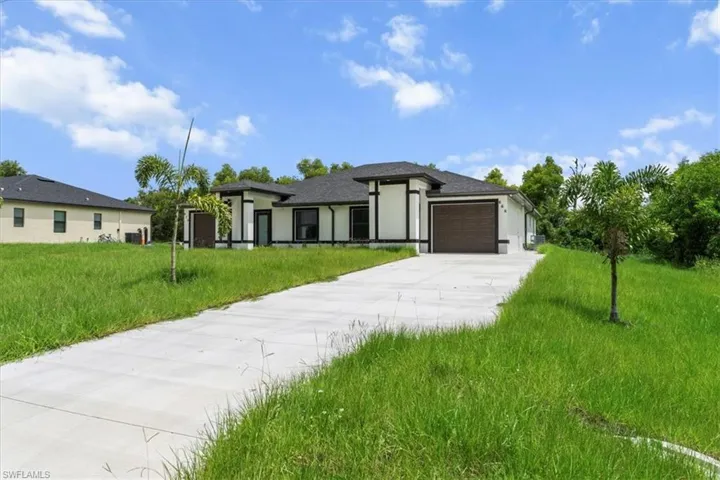 Prairie-style house featuring an attached garage, driveway, stucco siding, and a front yard