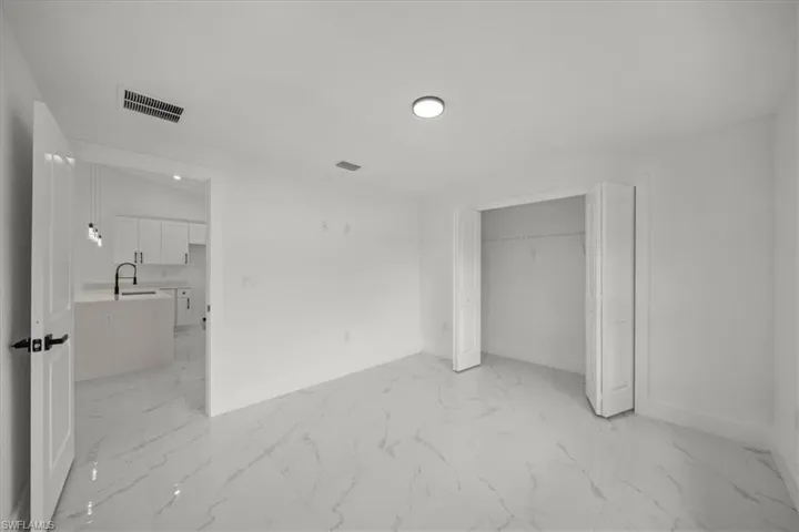 Unfurnished bedroom featuring light marble finish floors and a closet