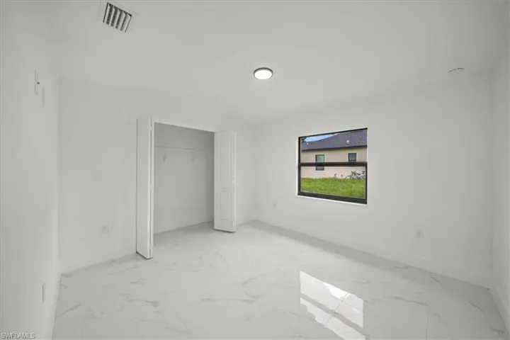 Unfurnished bedroom with light marble finish floors and a closet