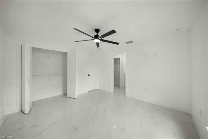 Unfurnished bedroom with light marble finish floors, a closet, and ceiling fan