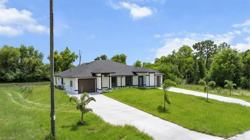 View of front facade featuring a garage, concrete driveway, a front lawn, and stucco siding