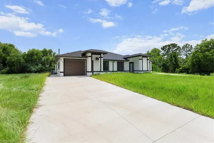 Prairie-style home featuring concrete driveway, an attached garage, stucco siding, and a front yard