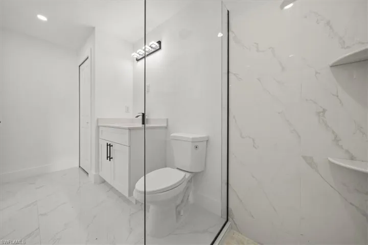 Bathroom featuring marble look tile flooring, vanity, and recessed lighting