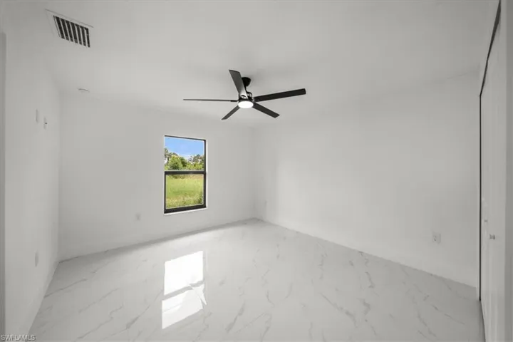 Empty room featuring light marble finish floors and ceiling fan