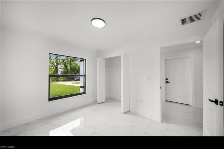 Unfurnished bedroom featuring light marble finish floors and a closet