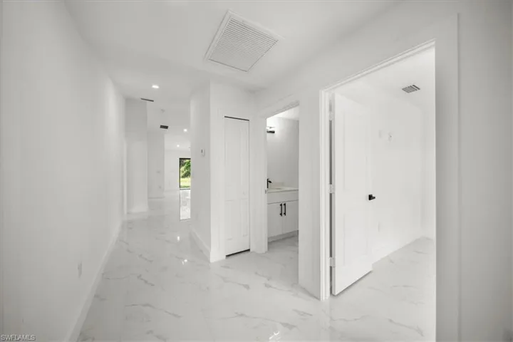 Hallway featuring light marble finish floors and recessed lighting