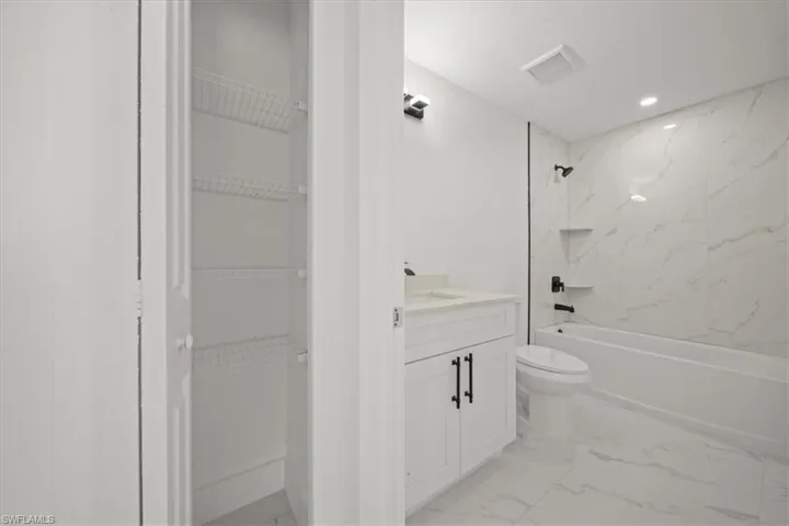 Full bathroom with vanity, marble finish flooring, bathtub / shower combination, recessed lighting, and a spacious closet