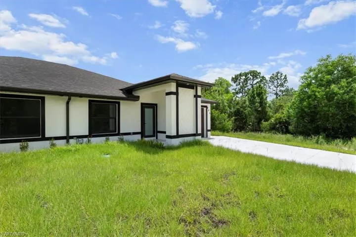 Back of property featuring stucco siding and roof with shingles