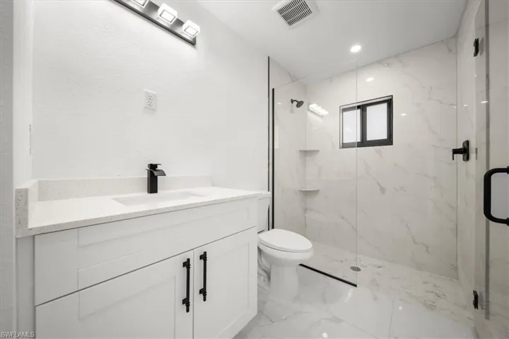 Bathroom with marble finish flooring, a marble finish shower, vanity, and recessed lighting