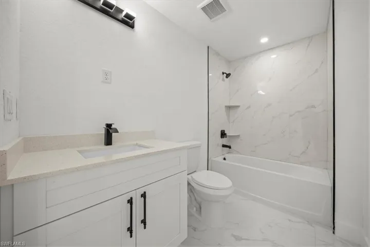 Full bath featuring marble finish flooring, vanity, washtub / shower combination, and recessed lighting
