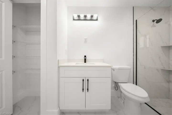 Bathroom featuring marble finish floors, a marble finish shower, vanity, and a spacious closet