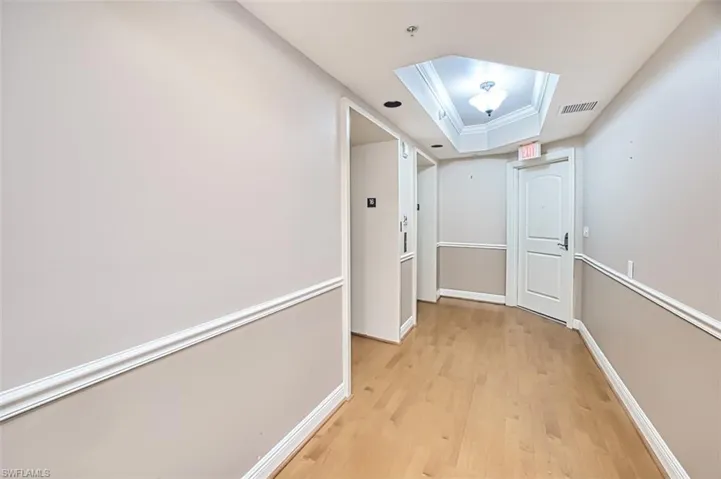 Hall featuring a raised ceiling and light hardwood / wood-style flooring
