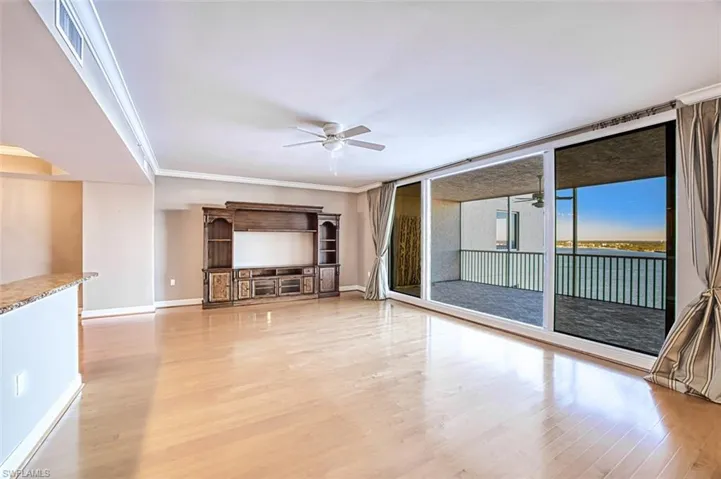 Unfurnished living room featuring hardwood / wood-style floors, ceiling fan, and crown molding