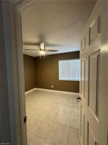 Spare room with a textured ceiling, light tile patterned floors, and a ceiling fan