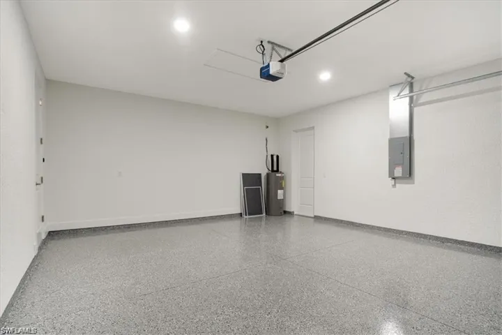 Garage with electric panel, a garage door opener, and water heater