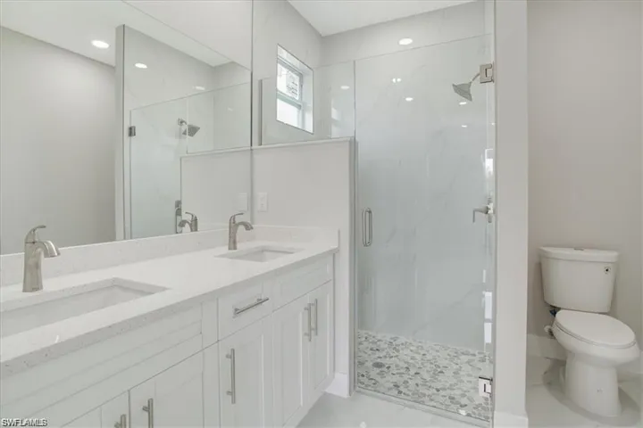 Bathroom with a shower with door, vanity, and toilet
