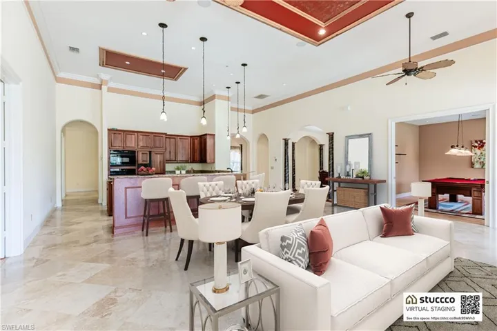Living room featuring a high ceiling, ceiling fan, ornamental molding, and light tile floors