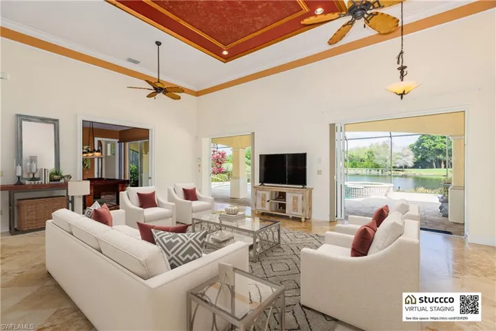 Tiled living room featuring a high ceiling, ornamental molding, ceiling fan, and a water view