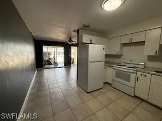 1 BR Kitchen with white appliances, white cabinets, open floor plan, and light countertops