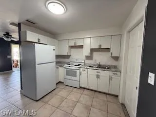 1 BR Kitchen with white appliances, light countertops, white cabinets, and light tile patterned flooring