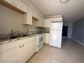 1 BR Kitchen featuring white appliances, white cabinetry, light countertops, and light tile patterned flooring