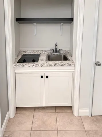 Efficiency Kitchen featuring white cabinets, black electric cooktop, open shelves, and light tile patterned flooring