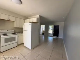 1 BR Kitchen featuring white appliances, light countertops, white cabinetry, and light tile patterned floors