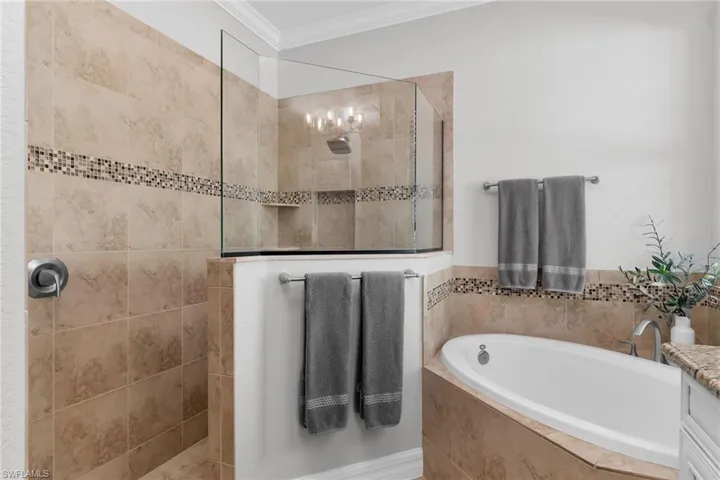 Bathroom with crown molding, a bath, vanity, and a walk in shower