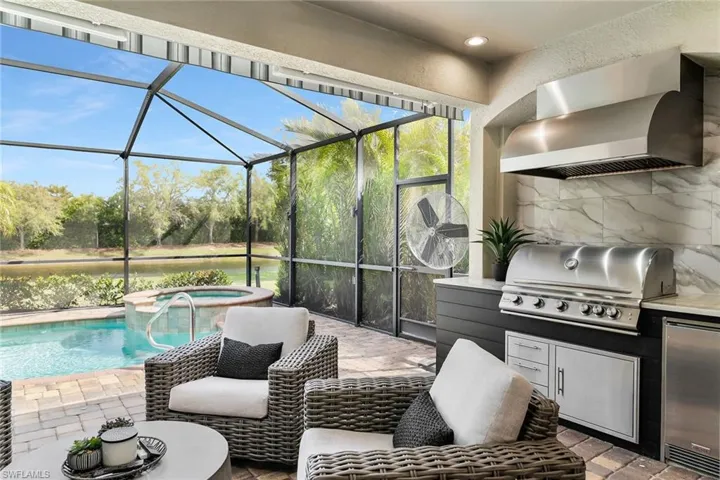 View of patio / terrace featuring area for grilling, glass enclosure, a sunroom, a pool with connected hot tub, and a water view