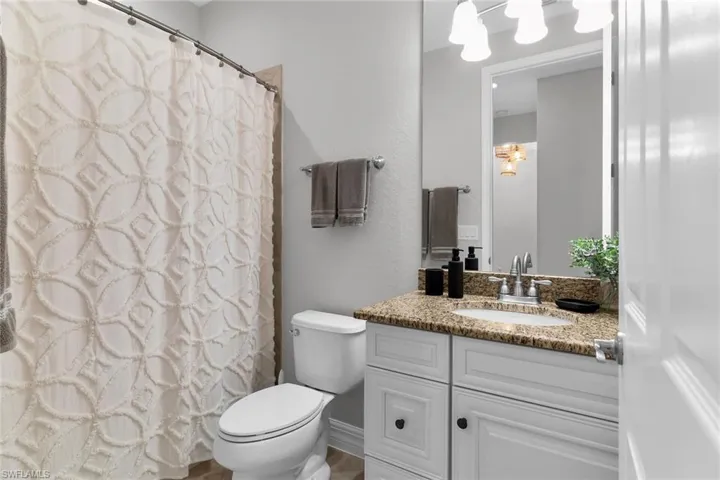 Full bathroom with vanity, curtained shower, and a textured wall