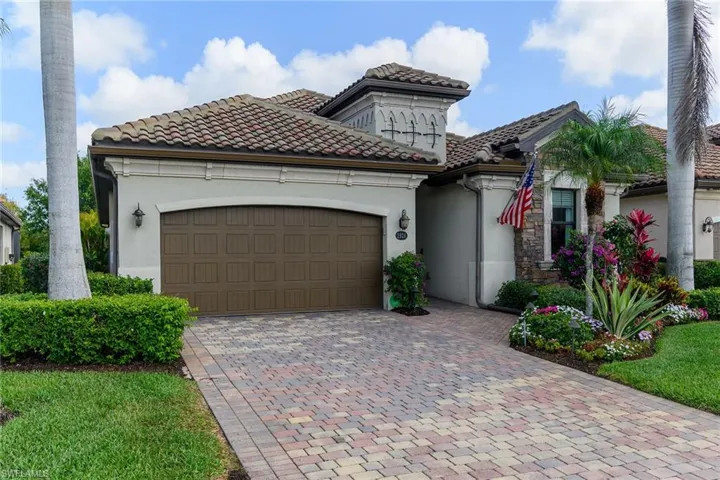 Mediterranean / spanish house with a garage, stucco siding, decorative driveway, and a tile roof